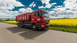 LKW fährt auf Straße vor Rapsfeld